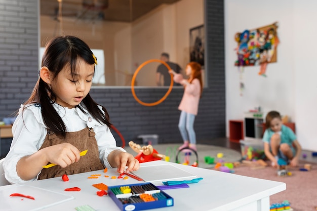 Kostenloses Foto mittleres schussmädchen, das am tisch spielt