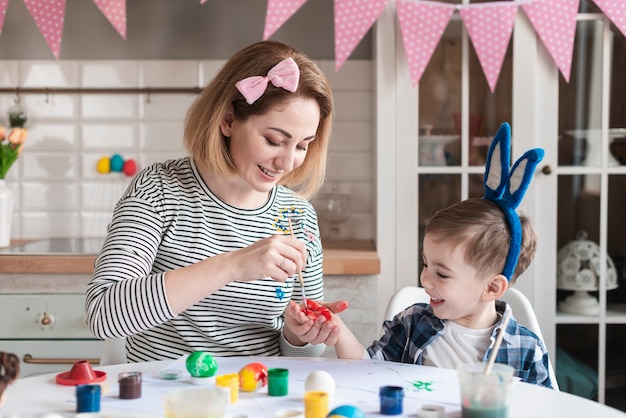 Kostenloses Foto mutter bringt ihrem sohn bei, wie man eier für ostern malt