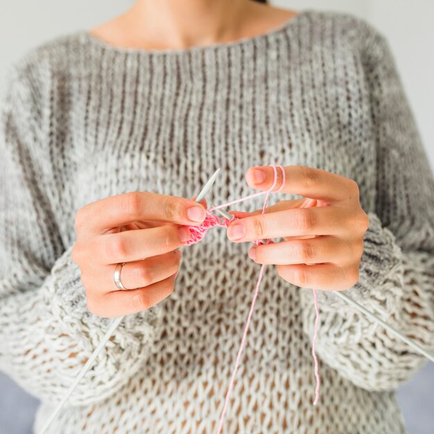 Nahaufnahme der Hand einer Frau, die mit rosa Thread häkelt