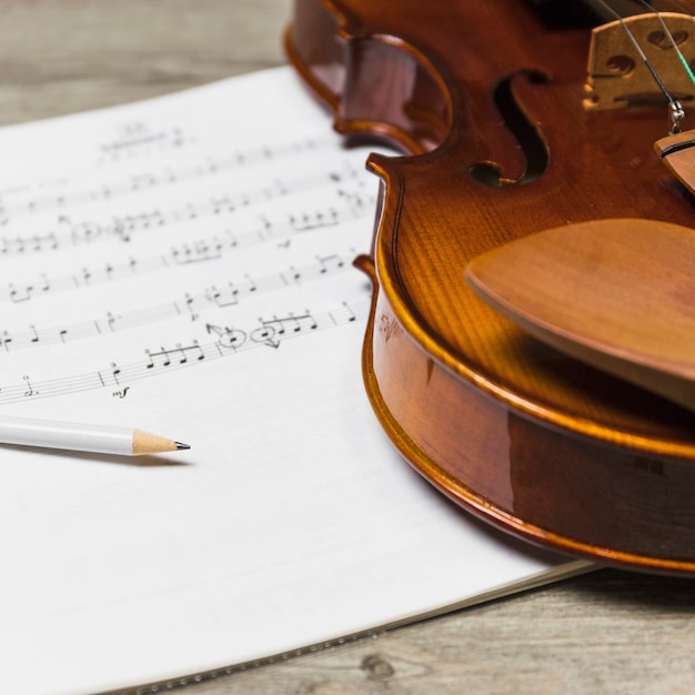 Kostenloses Foto nahaufnahme des bleistifts und der violine auf musiknote über dem holztisch