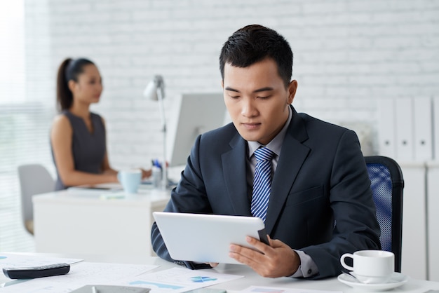 Kostenloses Foto nahaufnahme des mannes im formalwear, das am schreibtisch sitzt und am tablet-pc arbeitet