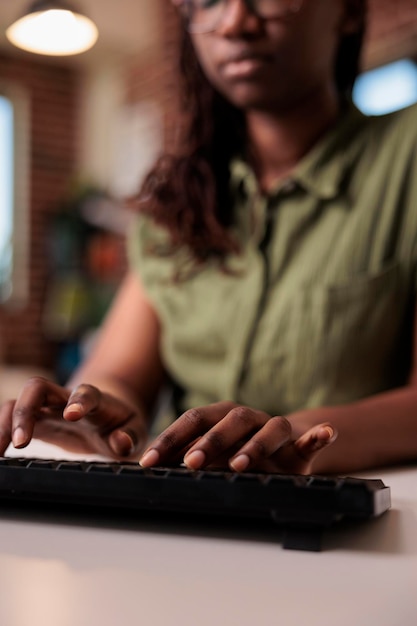 Kostenloses Foto nahaufnahme einer afrikanisch-amerikanischen programmiererin, die code auf der computer-tastatur schreibt, während sie aus dem wohnzimmer entfernt arbeitet.