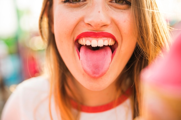 Kostenlose Foto nahaufnahme einer jungen frau, die zunge heraus haftet