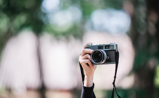 Kostenlose Foto nahaufnahme und selektiver fokus hände einer professionellen fotografin, die eine digitalkamera hält, um schnappschüsse im kopierraum des naturwaldes zu machen