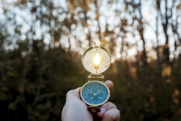 Kostenloses Foto nahaufnahmeaufnahme einer person, die einen kompass mit der sonne hält, die durch das loch scheint