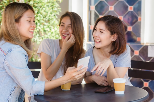 Kostenloses Foto nette asiatische junge frauen, die in trinkendem kaffee des cafés mit freunden sitzen und zusammen sprechen