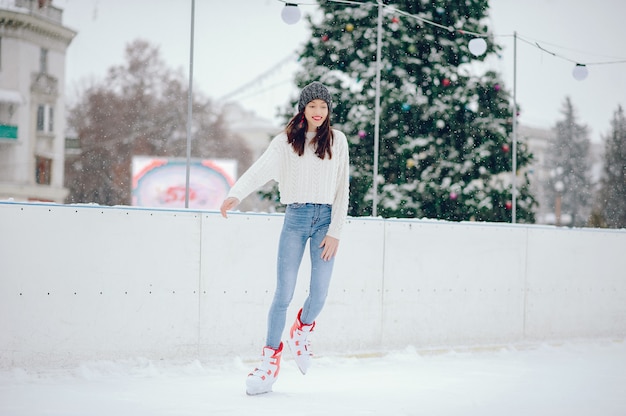 Nettes und schönes Mädchen in einer weißen Strickjacke in einer Winterstadt