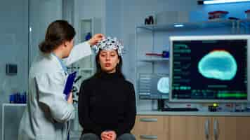 Kostenloses Foto neurologischer arzt, der ein eeg-headset prüft, um die diagnose von krankheiten und die behandlung des nervensystems des patienten zu erklären. wissenschaftlerforscher, der gehirnscan und tomographie auf monitor im labor analysiert