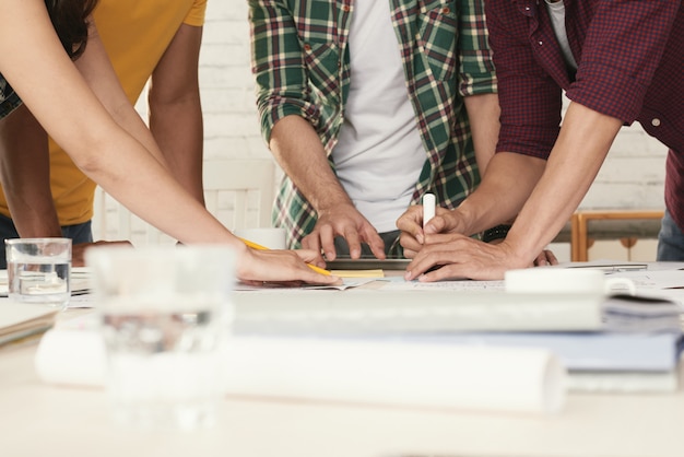 Nicht wiederzuerkennende beiläufig gekleidete Leute, die um den Tisch stehen und Brainstorming betreiben