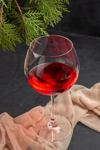 Kostenloses Foto oben blick auf köstlichen rotwein in einem glasbecher auf handtuch und tannenzweigen auf dunklem hintergrund