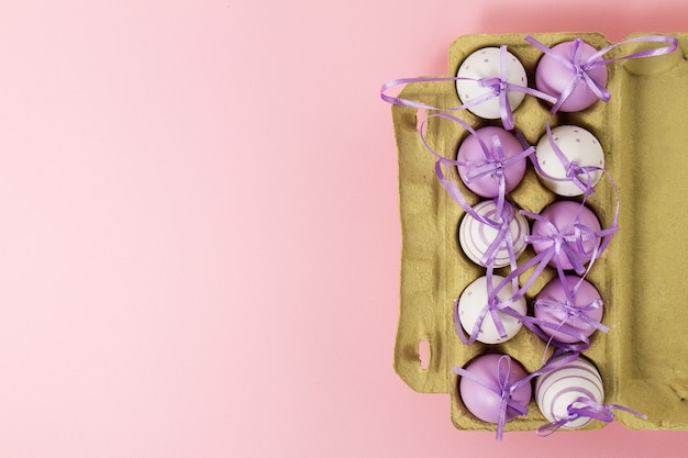 Kostenloses Foto ostern oder frühling, lebensmittelkonzept. frische eier im kasten für eier auf rosa pastell hintergrund. draufsicht.