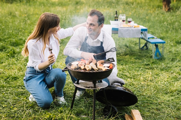 Kostenloses Foto paare, die einen grill in der natur tun