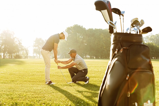 Kostenlose Foto personal trainer, der einem jungen männlichen golfer eine lektion erteilt