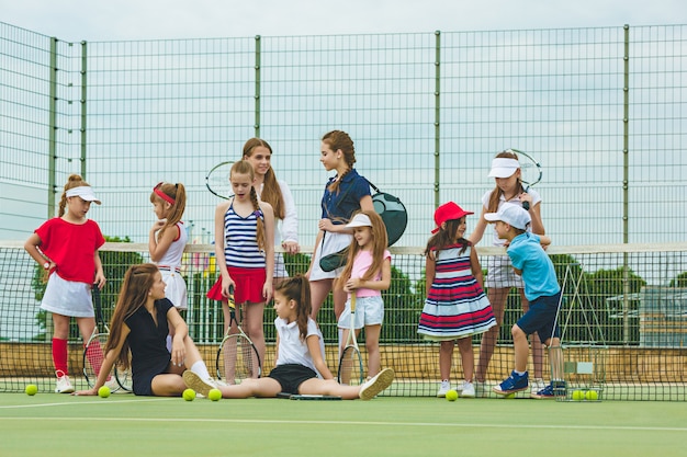 Kostenloses Foto porträt der gruppe von mädchen als tennisspieler, die tennisschläger gegen grünes gras des außenplatzes halten