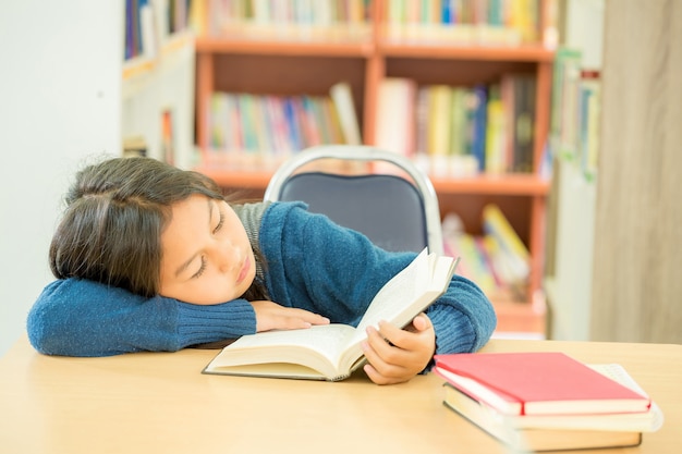 Kostenloses Foto porträt des klugen studenten mit offenem buch es in der collegebibliothek lesend