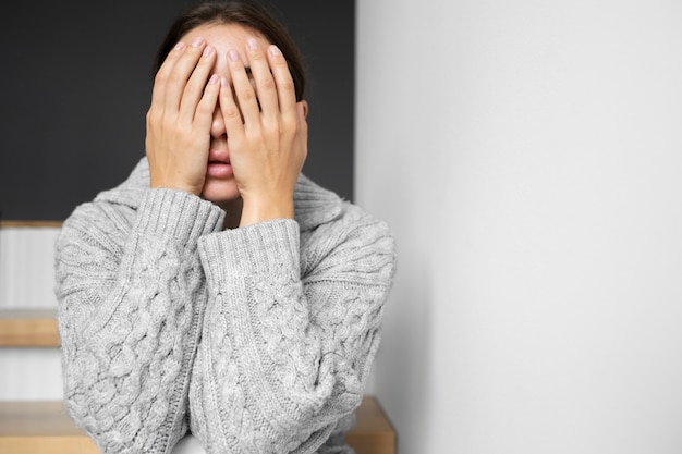 Kostenloses Foto porträt einer jungen frau mit geringem selbstwertgefühl, die zu hause auf der treppe sitzt