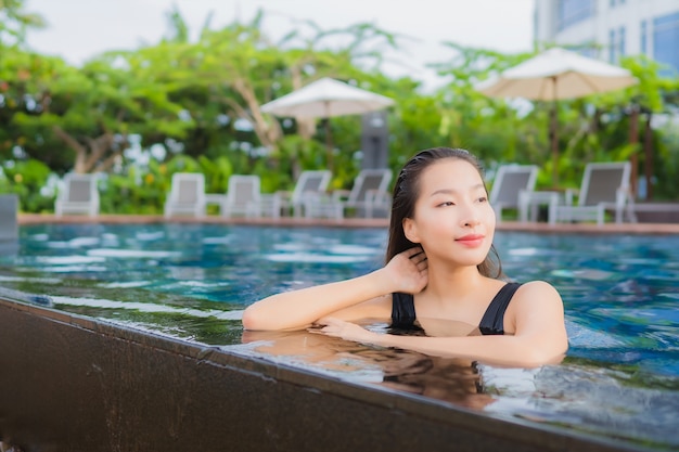 Kostenlose Foto porträt schöne junge asiatische frau freizeit entspannen lächeln um außenpool für urlaub