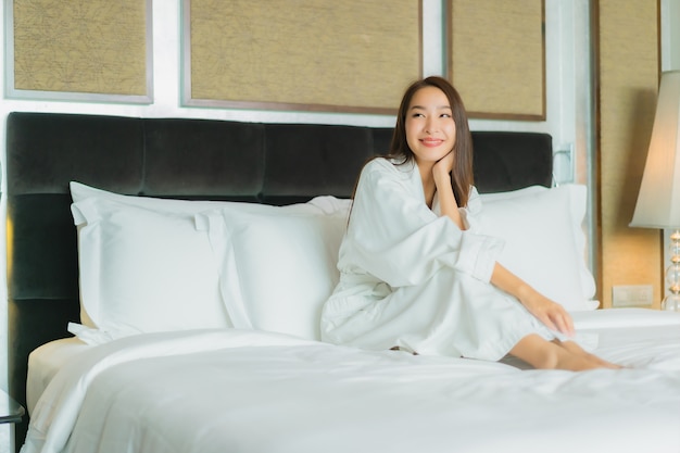 Kostenlose Foto porträt schöne junge asiatische frau lächeln entspannen auf dem bett im schlafzimmer interieur