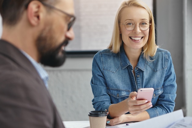 Positive weibliche Assistentin und bärtiger ernsthafter männlicher Unternehmer im Amt