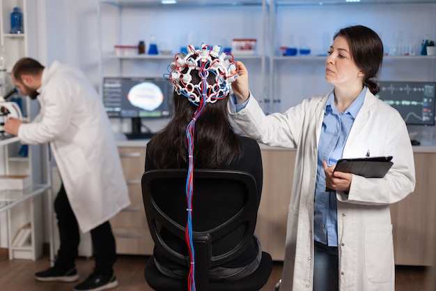 Kostenloses Foto professioneller arzt in neurowissenschaften, der behandlungen für neurologische erkrankungen entwickelt und die entwicklung von patienten untersucht. doktorforscher, der das eeg-headset anpasst und die gehirnfunktionen und den gesundheitszustand analysiert.