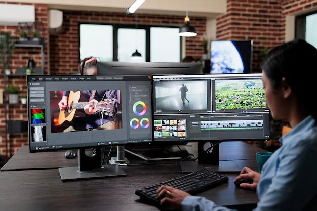 Kostenlose Foto professioneller filmmaterialeditor eines kreativen unternehmens, der an einer workstation mit mehreren monitoren sitzt, während er filmbilder bearbeitet. erfahrener videofilmer, der die videoqualität mit spezieller software verbessert.