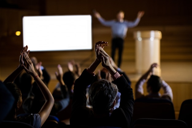 Kostenloses Foto publikum applaudiert redner nach konferenzpräsentation