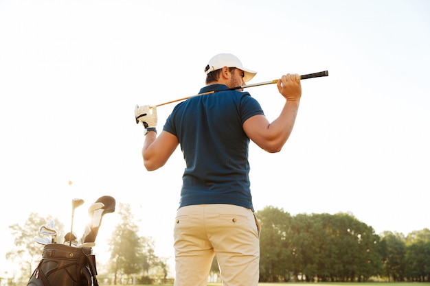 Kostenlose Foto rückansicht eines männlichen golfspielers auf dem platz mit einem vereinssack