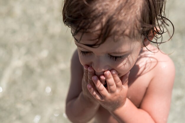 Schließen Sie herauf Kind mit geschlossenen Augen, die im Wasser spielen