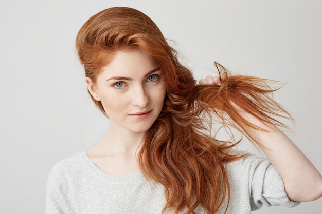 Kostenloses Foto schließen sie oben vom jungen schönen ingwermädchen, das berührendes haar lächelt.