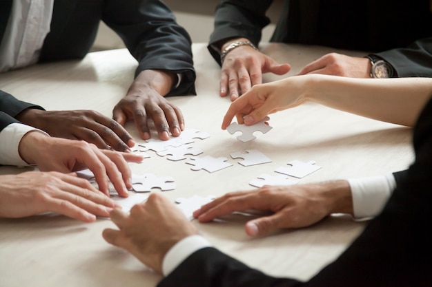 Kostenloses Foto schließen sie oben vom multiethnischen team, das leeres puzzlespielspiel löst.