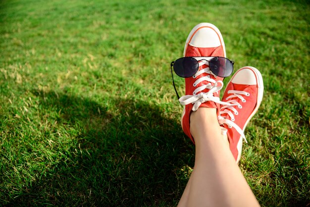 Schließen Sie oben von den Beinen in den roten Keds, die auf Gras liegen.