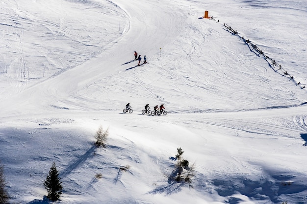 Kostenloses Foto schöne ansicht der leute, die über schneebedeckte berge in südtirol, dolomiten, italien radeln und ski fahren