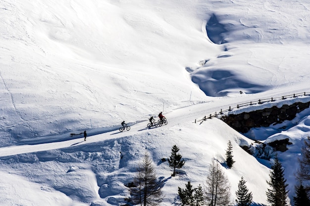 Kostenloses Foto schöne ansicht der leute, die über schneebedeckte berge in südtirol, dolomiten, italien radeln