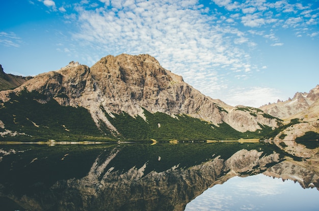 Kostenloses Foto schöne aufnahme eines felsigen berges neben einem see mit spiegelung im wasser