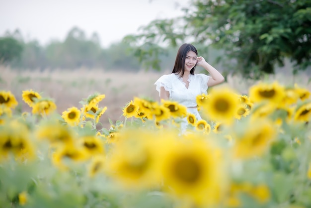 Kostenloses Foto schöne sexy frau in einem weißen kleid zu fuß auf einem feld von sonnenblumen