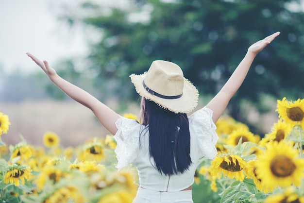 Kostenloses Foto schöne sexy frau in einem weißen kleid zu fuß auf einem feld von sonnenblumen