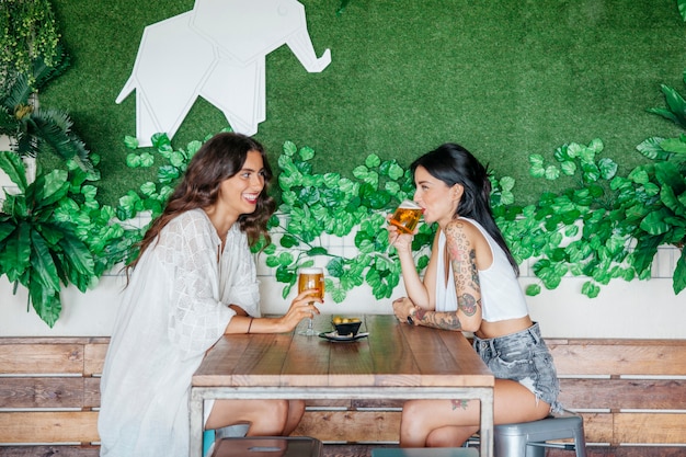 Kostenloses Foto seitenansicht der frauen trinken bier am tisch