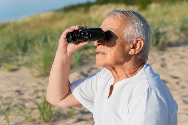 Kostenloses Foto seitenansicht des älteren mannes mit fernglas im freien