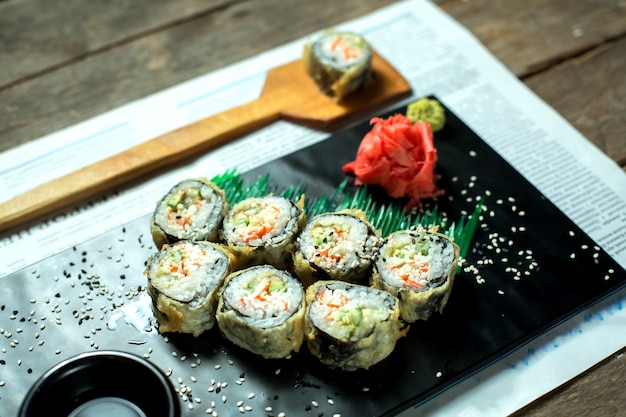 Kostenloses Foto seitenansicht des traditionellen japanischen tempura-sushi-maki des essens, serviert mit ingwer und sojasauce auf tafel