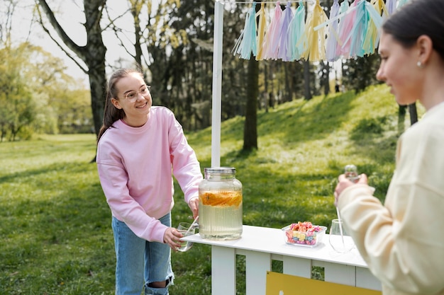 Kostenloses Foto seitenansichtmädchen, das frische limonade verkauft