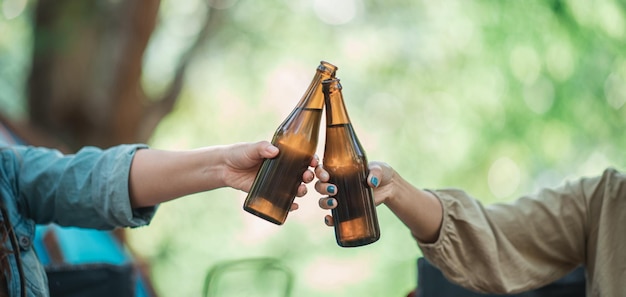 Kostenlose Foto selektiver fokus und nahaufnahme hände von frauen und freunden, die sich vor dem campingzelt entspannen sie genießen es, mit spaß und freude zusammen zu jubeln und bier zu trinken