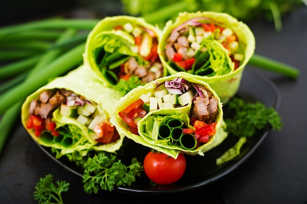 Kostenlose Foto shawarma aus saftigem rindfleisch, salat, tomaten, gurken, paprika und zwiebeln in fladenbrot mit spinat. diätmenü