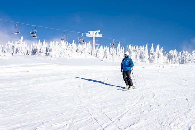 Kostenloses Foto skifahrer, die im bergresort mit seilbahnen im hintergrund den hügel hinunterfahren