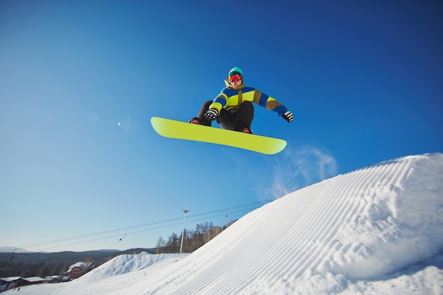 Kostenloses Foto snowboarder durch blauen himmel springen