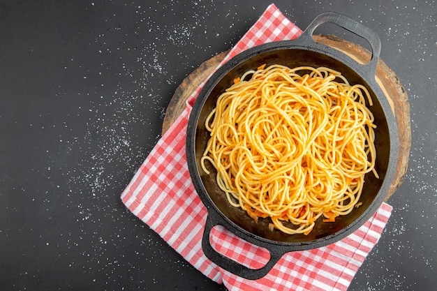 Kostenloses Foto spaghetti-pfanne mit draufsicht auf holzbrett auf dunklem hintergrund