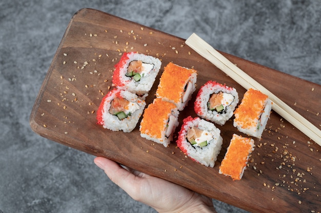 Kostenloses Foto sushi-rollen mit gelbem und rotem kaviar auf einem holzbrett.