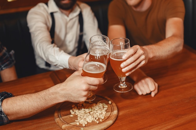 Kostenlose Foto treffen mit den besten freunden. drei glückliche junge männer in freizeitkleidung sprechen und trinken bier, während sie zusammen in der bar sitzen.