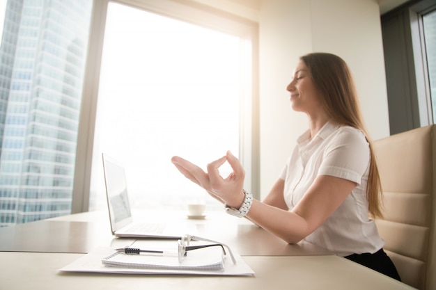 Kostenloses Foto Übendes yoga der ruhigen ruhigen geschäftsfrau bei der arbeit, meditierend im büro