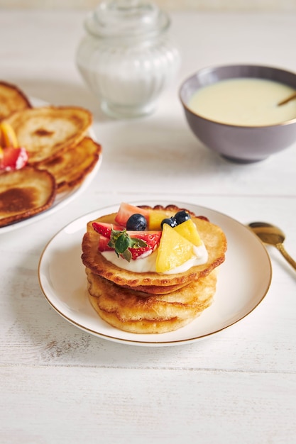 Kostenlose Foto vertikale aufnahme von köstlichen pfannkuchen mit früchten auf der oberseite beim frühstück