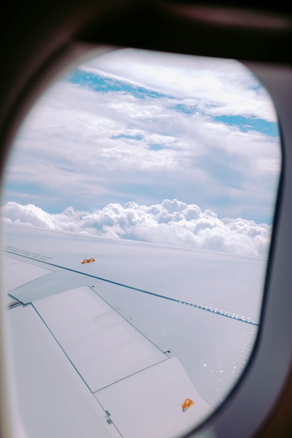 Kostenloses Foto vertikaler schuss der wolken, die von einem flugzeugfenster erfasst werden